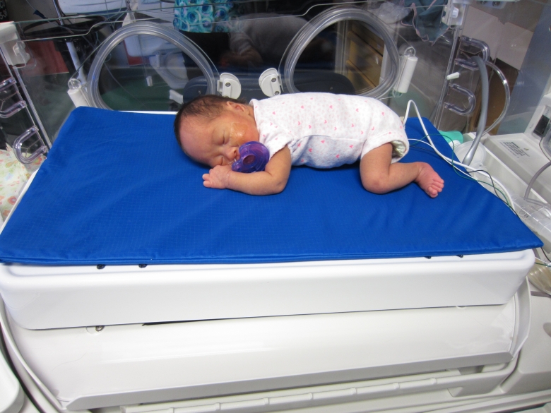 Baby laying on bed with blue blanket